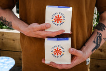 Load image into Gallery viewer, Person holding two boxes of Ritual Coffee coffee bags in front of a brown shirt.